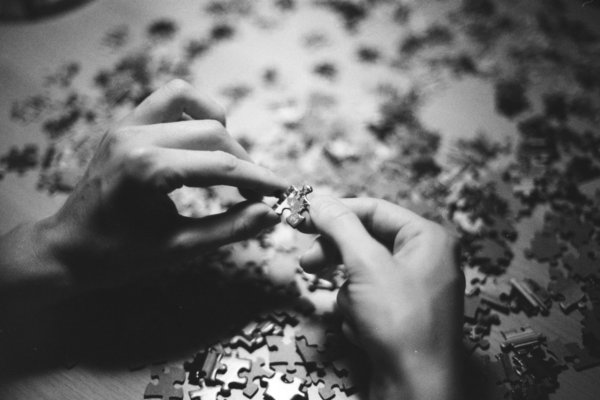 Two hands assembling a puzzle in black and white