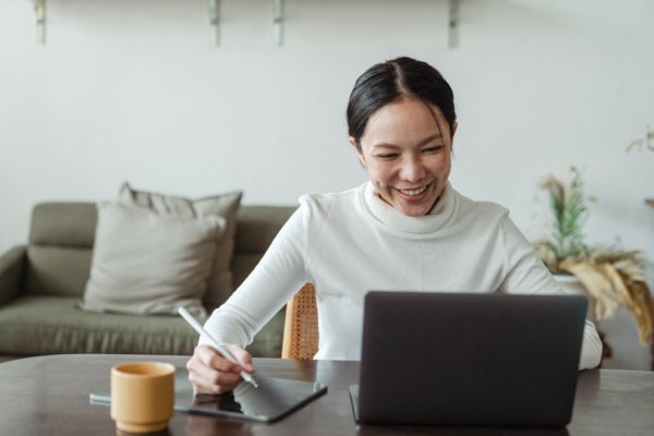 Woman smiling while working in the laptop seen from the front