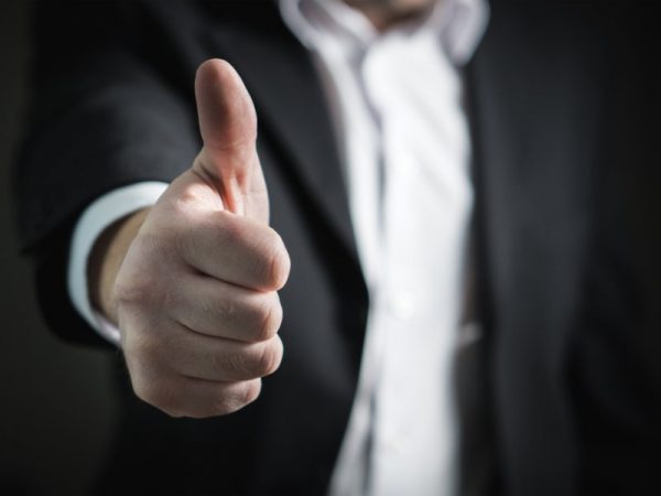 Man on a suit doing a thumbs-up gesture