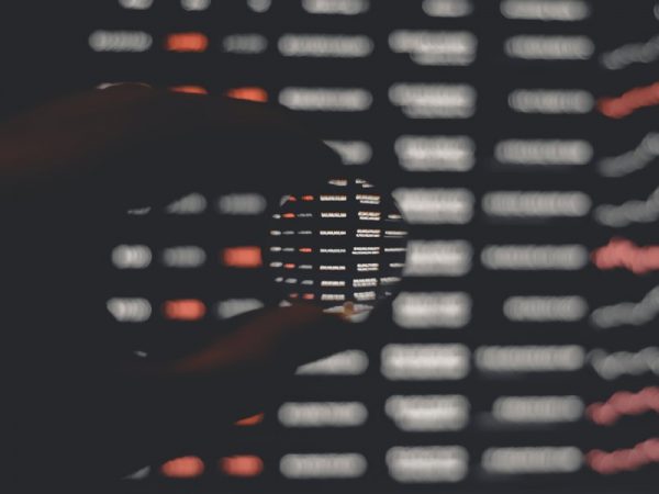 Hand holding a small lens on a dark background with white and red bars